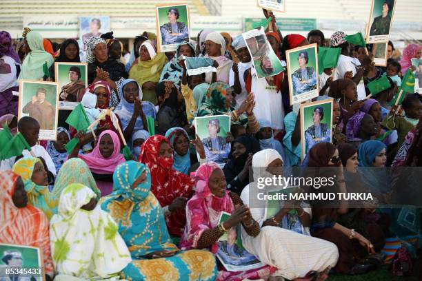 Mauritanian women hold pictures depicting Libyan leader Moamer Kadhafi during a ceremony to mark the birth of Prophet Mohammad on March 10 in...