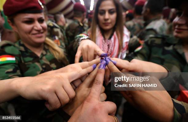 Female members of a Kurdish Peshmerga battalion show their ink-stained fingers after casting their vote in the Kurdish independence referendum in...