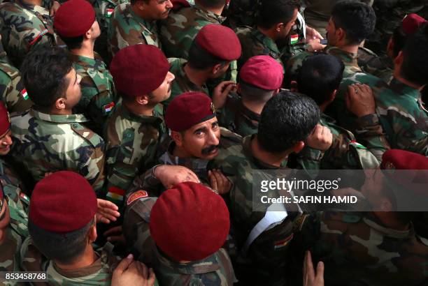 Members of a Kurdish Peshmerga battalion queue up outside a polling station in Arbil as they wait to cast their vote in the Kurdish independence...