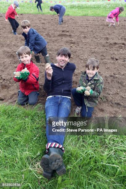 Alex James is helped planting potatoes by Simon Courtney and Ewan Wright from Kingham Primary School at his farm near Kingham, Oxfordshire. The...
