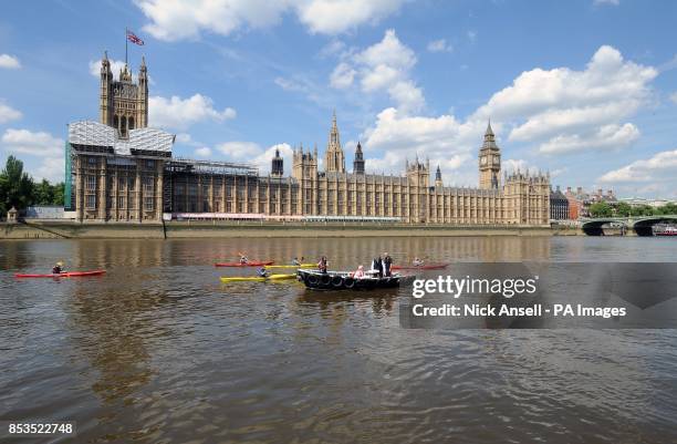 Kayakers pass by Zac Goldsmith MP and members from the Sustainable Eel Group as they release 10,000 juvenile eels into the River Thames from a boat...