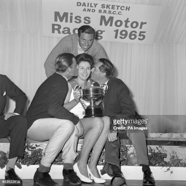 Jackie Peterson, of Saltdean, Brighton, holds the trophy after being elected 'Miss Motor Racing 1965' at Brands Hatch, Kent. She is being...