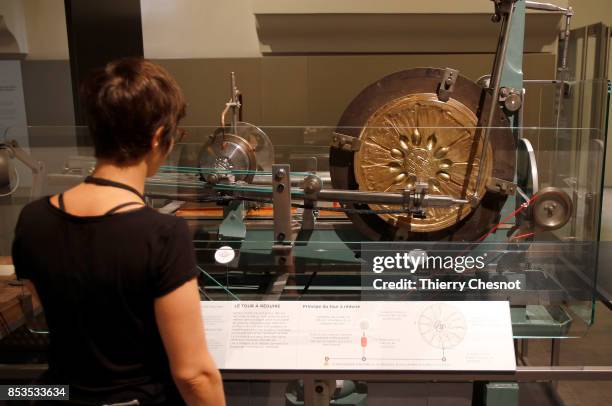 Woman looks at a reducing machine used to mint coins during the press visit at the "Monnaie de Paris" on September 25, 2017 in Paris, France. After...