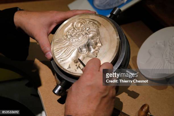 Craftman engraves a platinum used as a mold for a medal during the press visit at the "Monnaie de Paris" on September 25, 2017 in Paris, France....