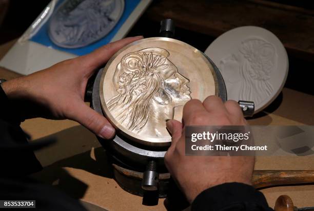 Craftman engraves a platinum used as a mold for a medal during the press visit at the "Monnaie de Paris" on September 25, 2017 in Paris, France....