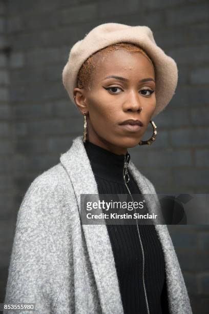Fashion blogger Irene Iredia wears a Miss guided dress and jacket, Urban Outfitters hat and earrings on day 1 of London Womens Fashion Week...