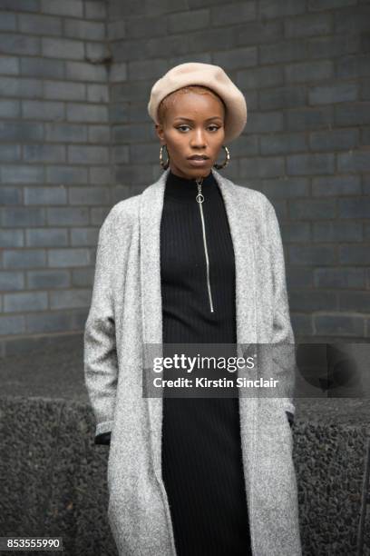 Fashion blogger Irene Iredia wears a Miss guided dress and jacket, Urban Outfitters hat and earrings on day 1 of London Womens Fashion Week...