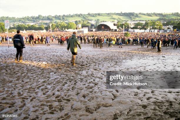 Photo of CROWDS and FANS and FESTIVALS and MUD , the crowd stand in a huge field of mud, the slick can be seen clearly in the foreground