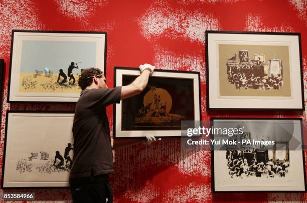 Worker hanging Banksy's prints at a press preview for the exhibition Banksy: The Unauthorised Retrospective, curated by Steve Lazarides, at S|2...