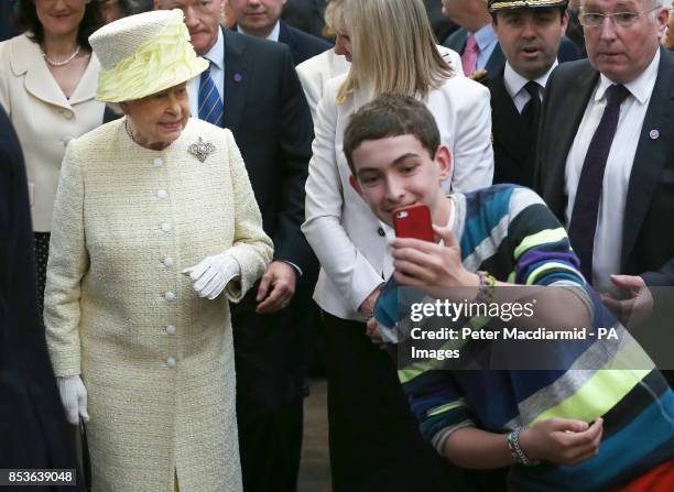 Teenager tries to take a selfie infront of Queen Elizabeth II during a walk around St. Georges Market in Belfast, on day two of their visit to...