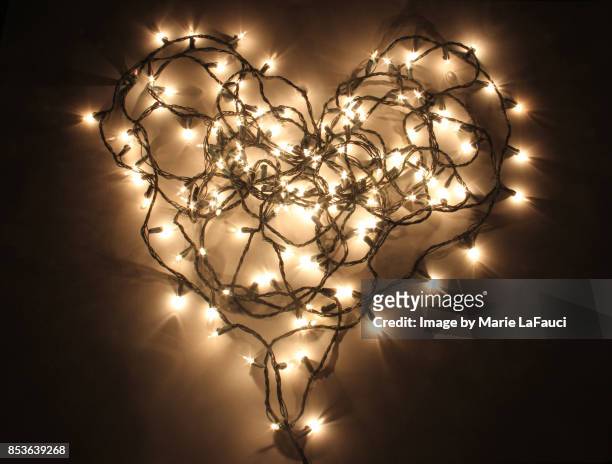 heart shaped christmas lights lit up in the dark - haz de luz fotografías e imágenes de stock