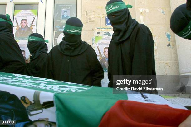 Masked activists from the militant Islamic group Hamas mourn around the mock coffin of Palestinian suicide bomber Dia Hussein Tawil, pictured in the...