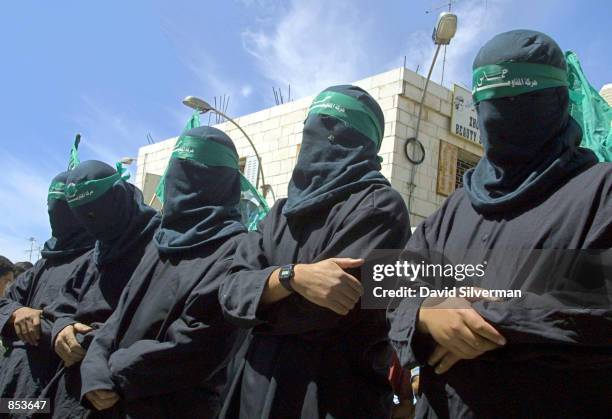 Masked activists from the militant Islamic group Hamas mourn around the mock coffin of Palestinian suicide bomber Dia Hussein Tawil during a symbolic...