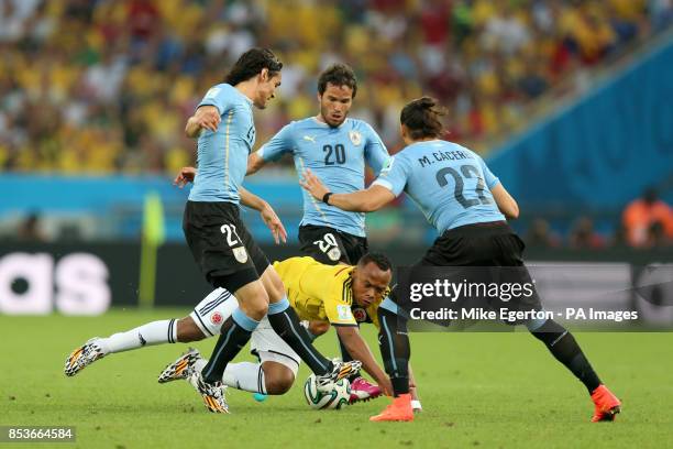 Colombia's Juan Zuniga goes down under a challenge from Uruguay's Edinson Cavani Martin Cacares and Alvaro Gonzalez during the FIFA World Cup, Round...