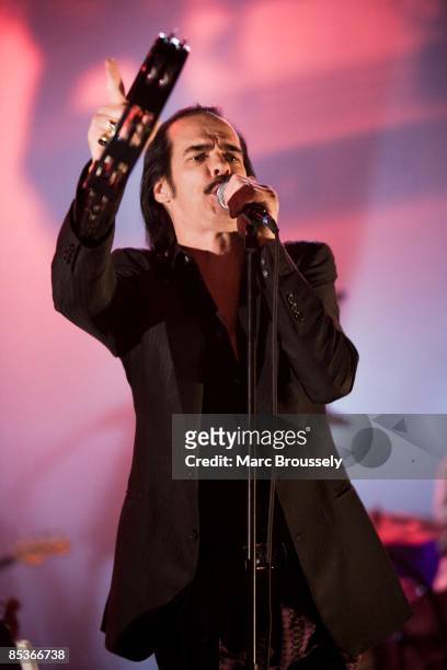 Photo of Nick CAVE & THE BAD SEEDS and Nick CAVE, Nick Cave performing on stage, tambourine