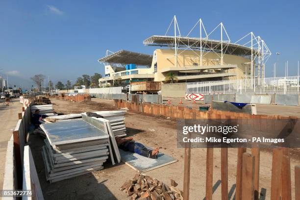 Olympic venues under construction for the Rio 2016 Games as a site workers take a nap in the foreground