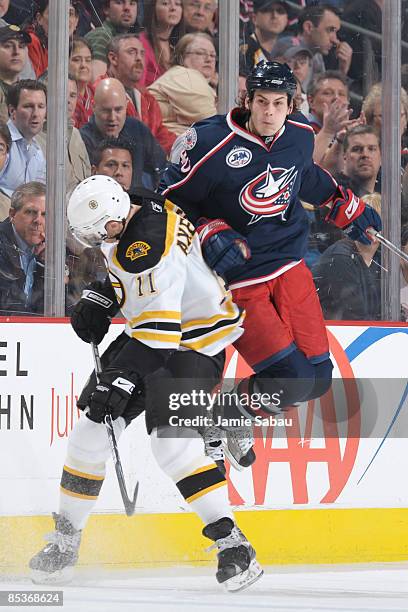 Forward Jared Boll of the Columbus Blue Jackets leaps to avoid a check by forward P.J. Axelsson of the Boston Bruins on March 10, 2009 at Nationwide...