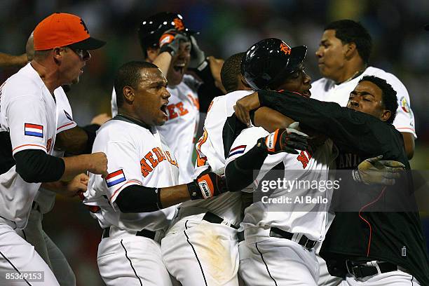 Yurendell de Caster of the Netherlands is mobbed by his teammates after driving in the the winning run on an error by Willy Aybar of the Dominican...