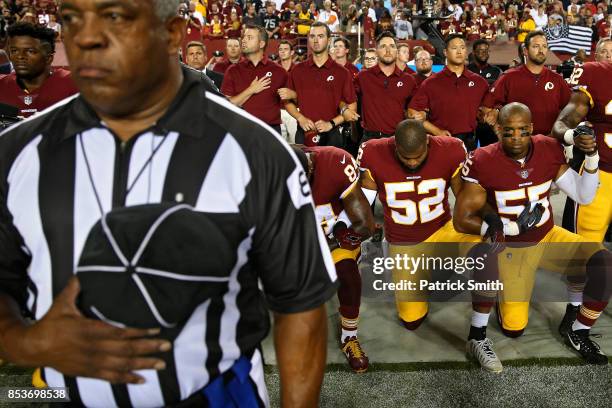 Ryan Anderson, Chris Carter and Niles Paul of the Washington Redskins lock arms as they kneel alongside standing coaching staff and teammates during...