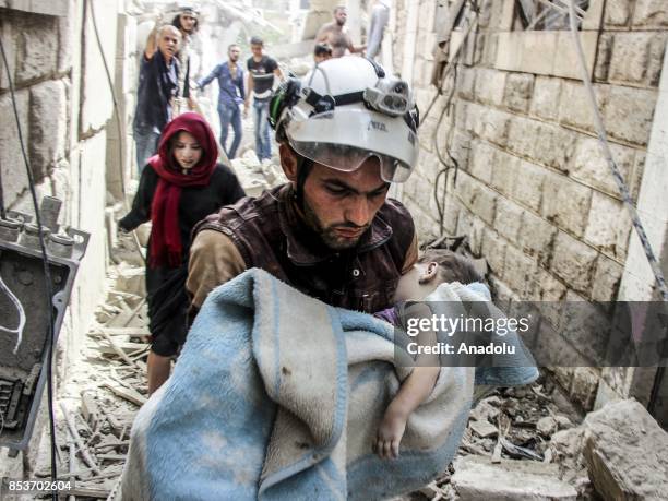 Search and rescue member holds a baby wrapped with a blanket after Assad Regime's forces carried out air strikes over the de-conflict zone, at the...