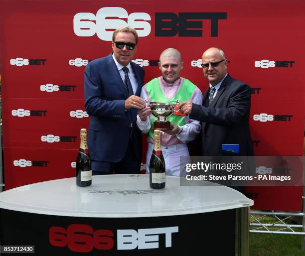 Harry Redknapp presents the winning trophy to Heaven's Guest jockey Tony Hamilton and trainer Richard Fahey after winning the 666BET Burbury cup...