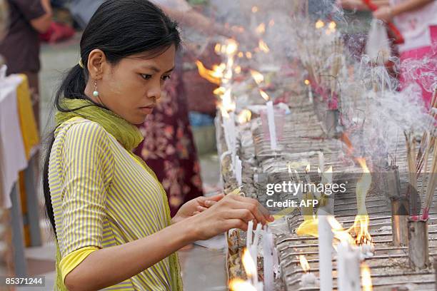 Myanmar girl lights candles at the famous Shwedagon Pagoda on the occasion of the Tabaung Full Moon Festival, in Yangon on March 10, 2009. During the...