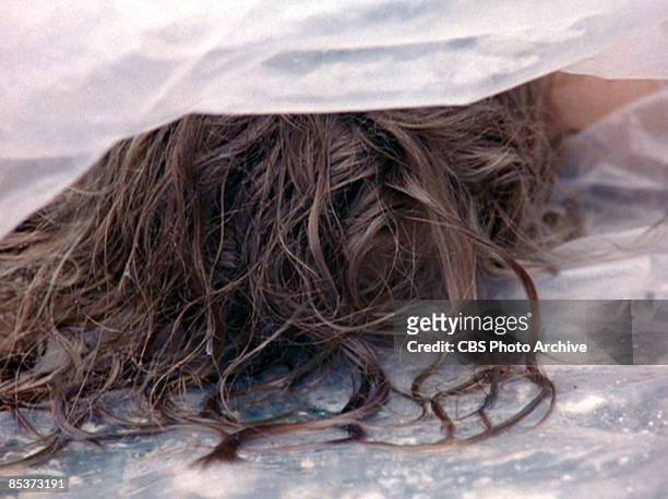 Close-up of German-born American actress Sheryl Lee lies, wrapped in a plastic sheet, on a rocky beach in a scene screen grab from the pilot episode...