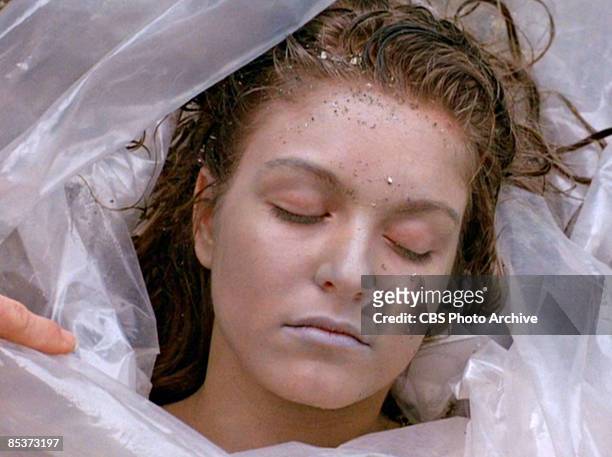 Close-up of German-born American actress Sheryl Lee lies, wrapped in a plastic sheet, on a rocky beach in a scene screen grab from the pilot episode...