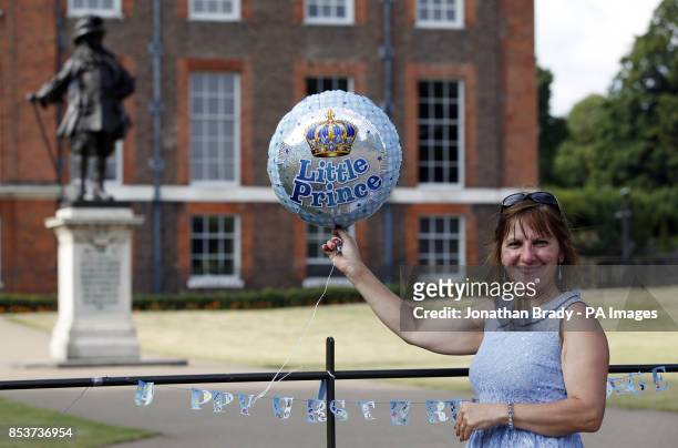 Kathy Martin from Beckenham, Kent ties a balloon to railings at the gates of Kensington Palace, London, in celebration of Prince George's first...