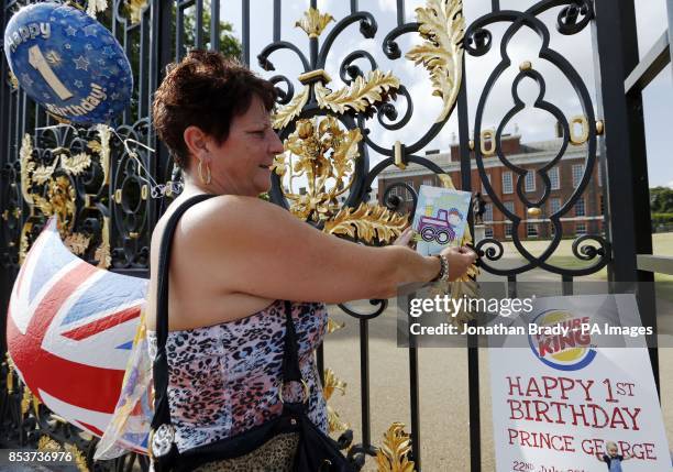 Sharon Kelshaw from Swansea places a birthday card on the gates of Kensington Palace, London, in celebration of Prince George's first birthday.