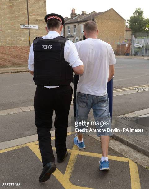 Suspect is led away as City of London Police execute a warrant at an address in Peckham, London, in connection with a criminal ring linking Russian...