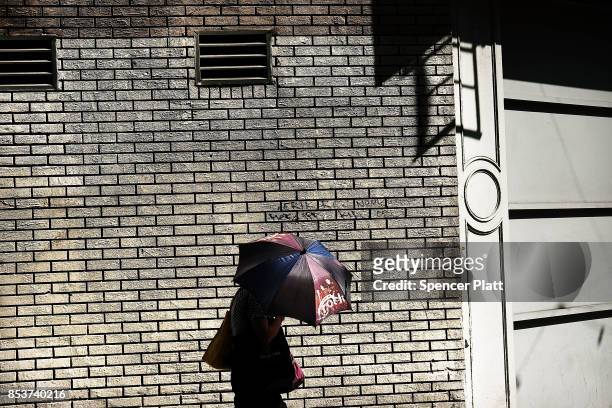 Woman walks down a Manhattan street on an unseasonably warm afternoon on September 25, 2017 in New York City. Despite officially entering fall last...