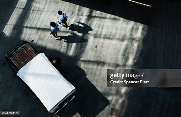 People walk along the Brooklyn waterfront on an unseasonably warm afternoon on September 25, 2017 in New York City. Despite officially entering fall...