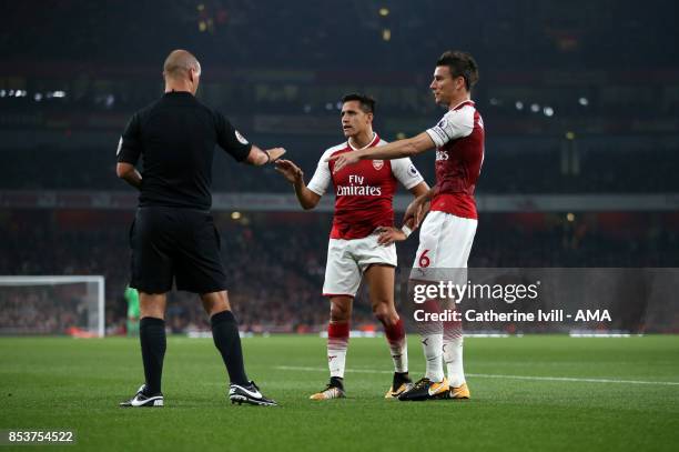 Referee Bobby Madley talks to Alexis Sanchez and Laurent Koscielny of Arsenal during the Premier League match between Arsenal and West Bromwich...