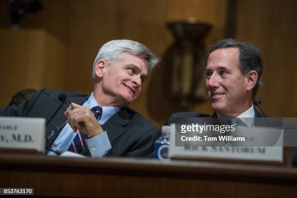 Sen. Bill Cassidy, R-La., and former Sen. Rick Santorum, R-Pa., confer during a Senate Finance Committee hearing on the proposal by Cassidy and Sen....