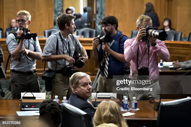 Senator Lindsey Graham, a Republican from South Carolina, bottom center, stays seated during a disruption in a Senate Finance Committee hearing to...