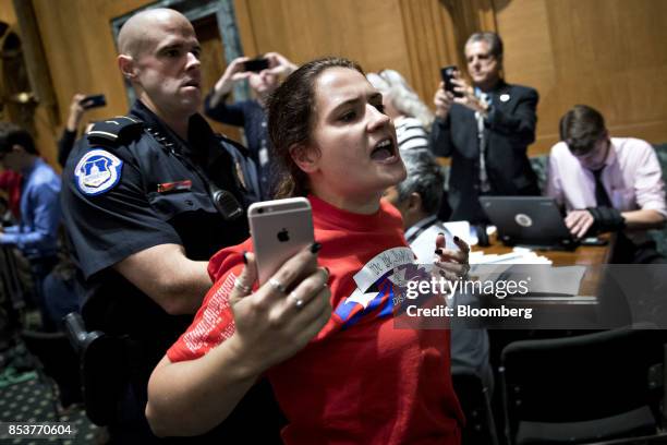 Member of the disability rights group ADAPT is escorted out of a Senate Finance Committee hearing to consider the Graham-Cassidy-Heller-Johnson...