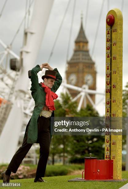 Man in costume tests his strength on the High Striker during a photo call for the London Dungeon's Carnivale side show, featuring a giant 'Jeremy...