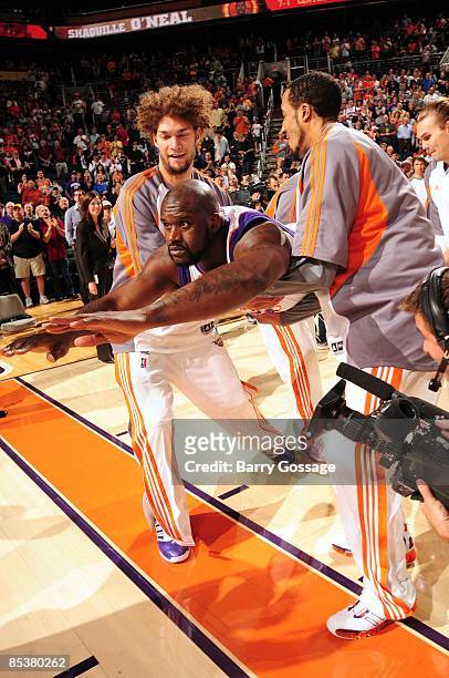 Shaquille O'Neal of the Phoenix Suns does his Superman impression with the help of teammates Robin Lopez and Courtney Sims prior to the game against...