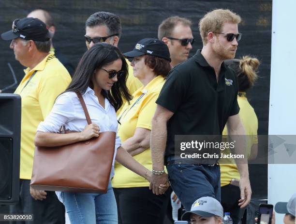 Prince Harry and Meghan Markle hold hands a Wheelchair Tennis match during the Invictus Games 2017 at Nathan Philips Square on September 25, 2017 in...