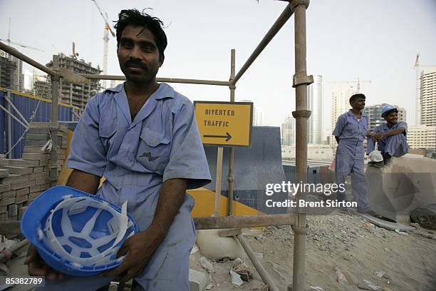 An exhausted migrant construction labourer working in the Dubai Marina area waits with his fellow labourers to board a bus which will take them back...