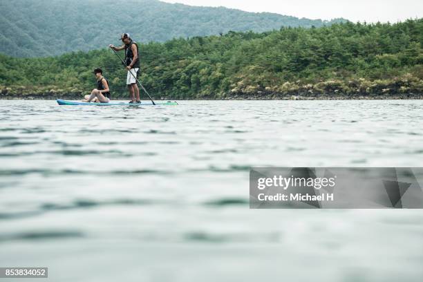 couple on paddle board in lake - paddle board men imagens e fotografias de stock