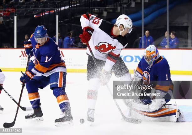 Thomas Greiss and Thomas Hickey of the New York Islanders defend against Ben Thomson of the New Jersey Devils during the first period during a...