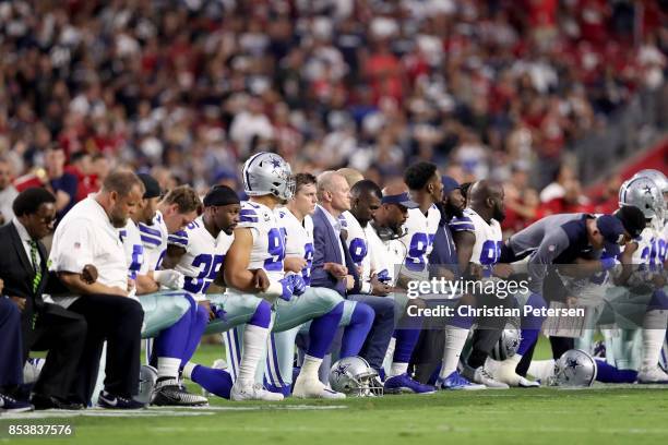 Members of the Dallas Cowboys link arms and kneel during the National Anthem before the start of the NFL game against the Arizona Cardinals at the...