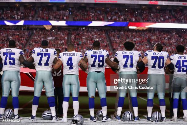 Quarterback Dak Prescott of the Dallas Cowboys links arms with teammates offensive tackle Tyron Smith and offensive guard Chaz Green during the...