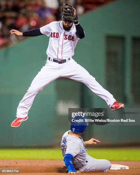 Deven Marrero of the Boston Red Sox leaps after catching a ball to tag out Ryan Goins of the Toronto Blue Jays as he attempts to steal second base...