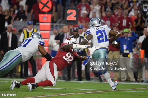 Running back Ezekiel Elliott of the Dallas Cowboys slips by Defensive end Frostee Rucker of the Arizona Cardinals during the first half of the NFL...