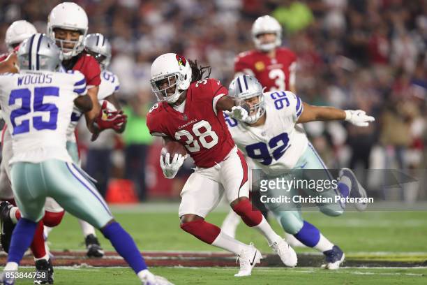 Running back Andre Ellington of the Arizona Cardinals slips past defensive tackle Brian Price of the Dallas Cowboys during the first halfof the NFL...