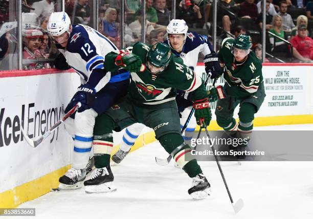 Winnipeg Jets right wing Buddy Robinson and Minnesota Wild center Pat Cannone ballet for the puck along the boards during a preseason NHL game...