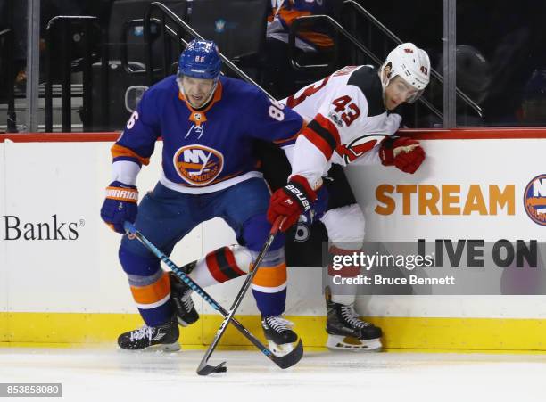 Nikolay Kulemin of the New York Islanders and Ben Thomson of the New Jersey Devils battle for the puck during the third period during a preseason...